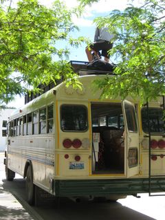 An instructor loads packs onto the top of a bus.