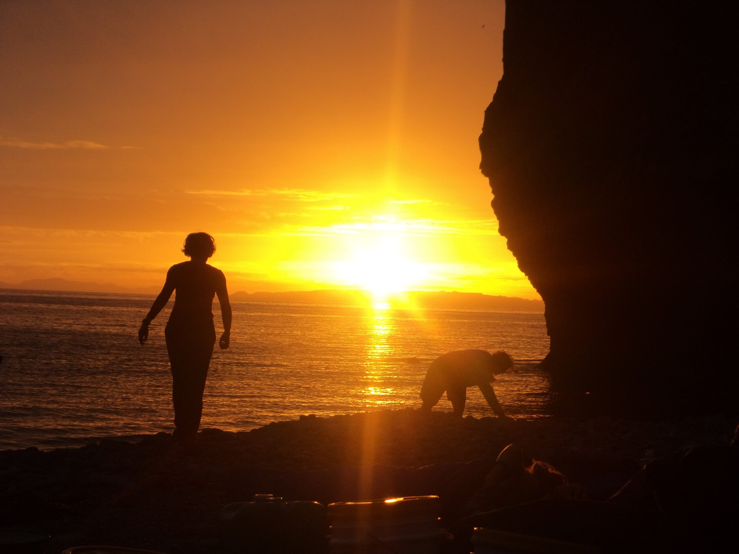 Students set up camp on the coast at sunset