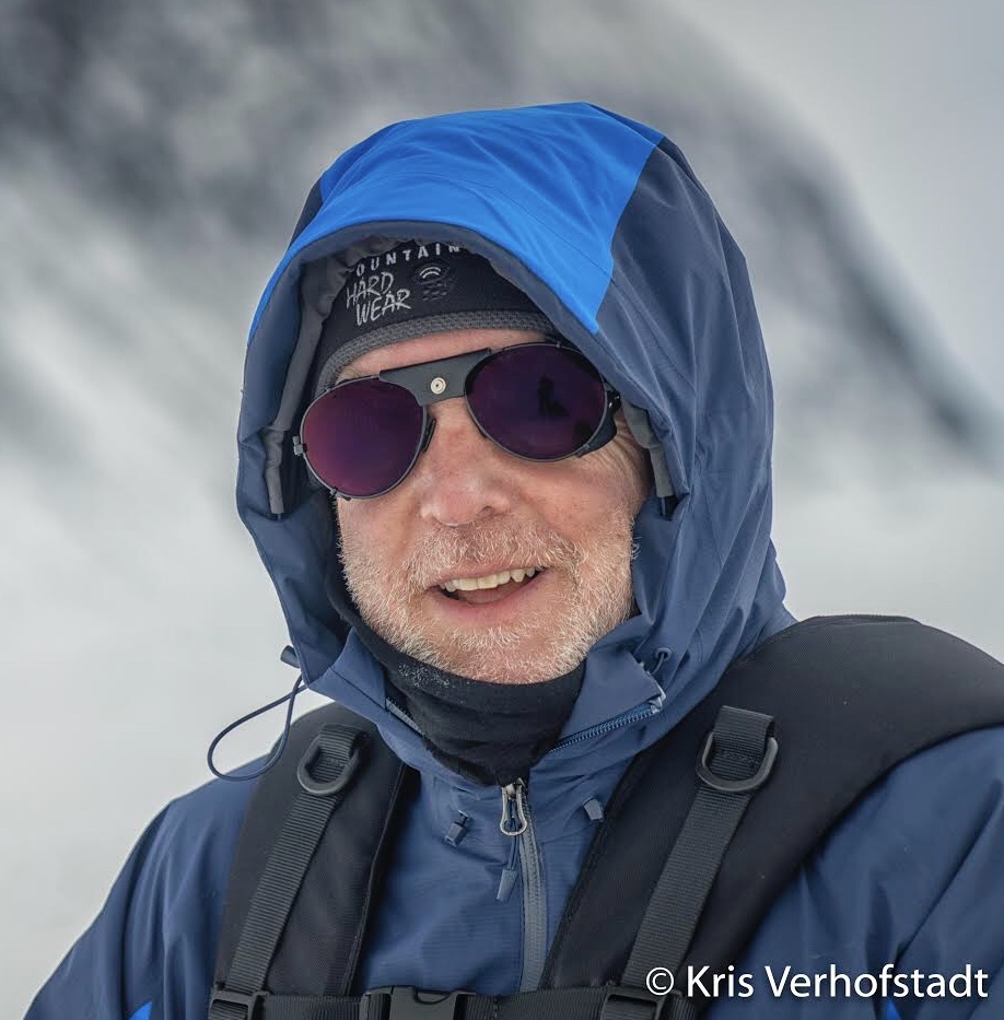 Close up of Eric wearing sunglasses and a hooded jacket for hiking