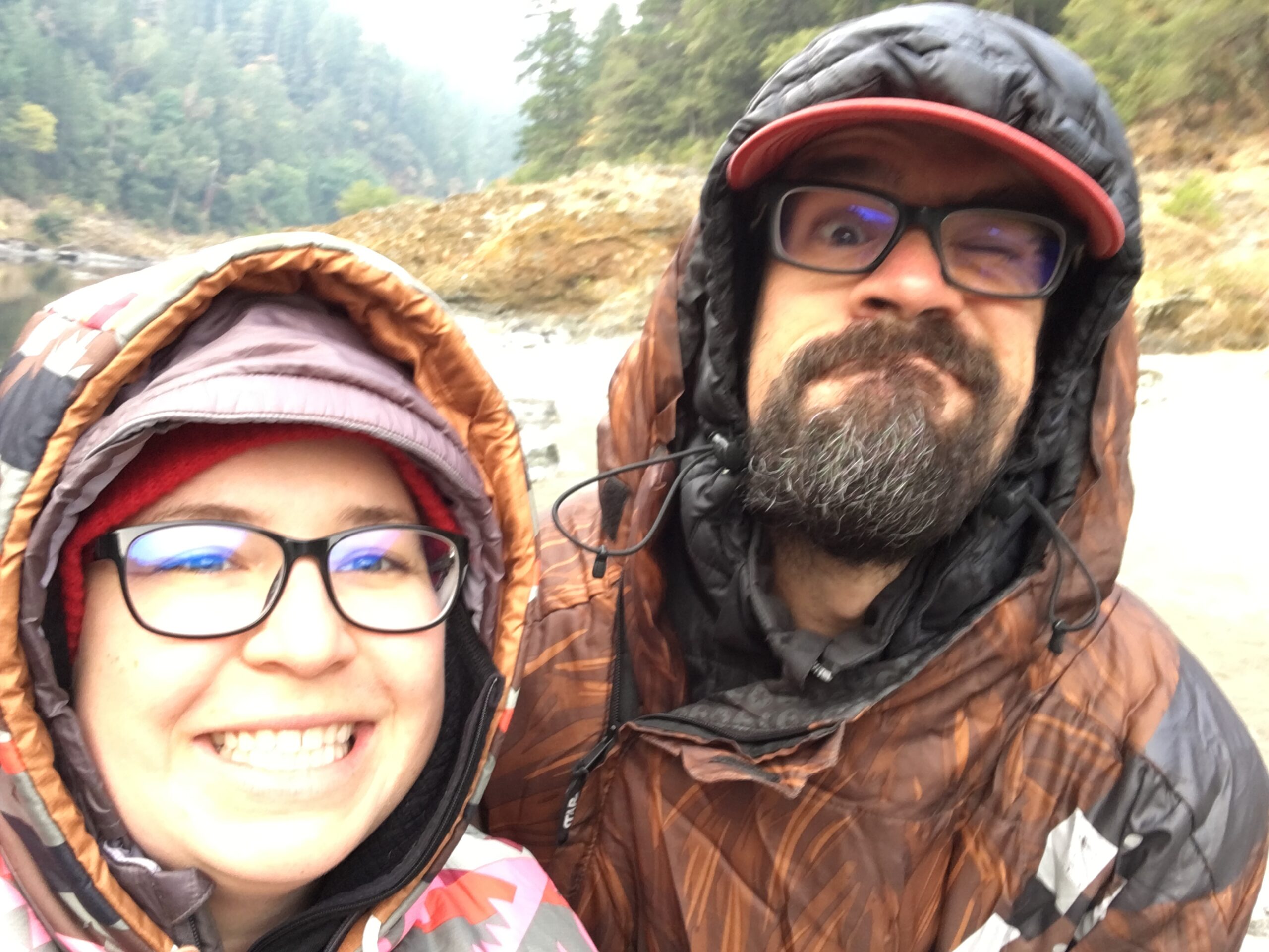 Ashley and Kyle Drake smile while wearing hooded outdoor jackets