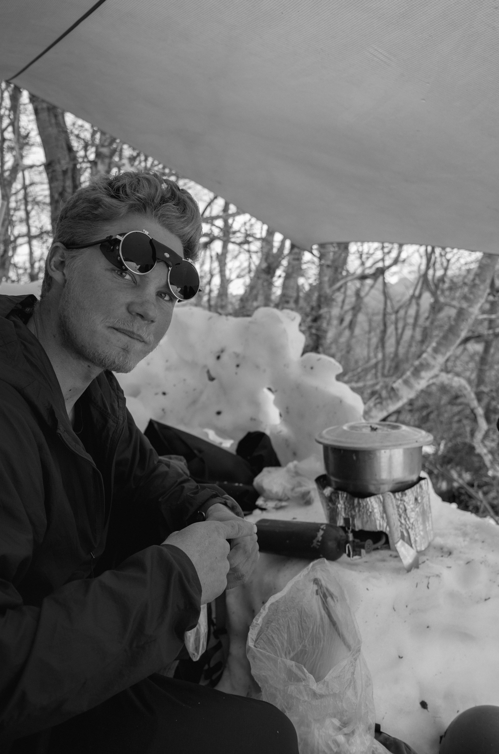 Person cooking on a camp stove in a snow kitchen