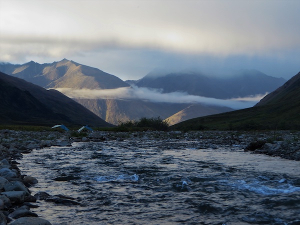 NOLS camp kitchen in the Brooks Range seen across river with mountains behind