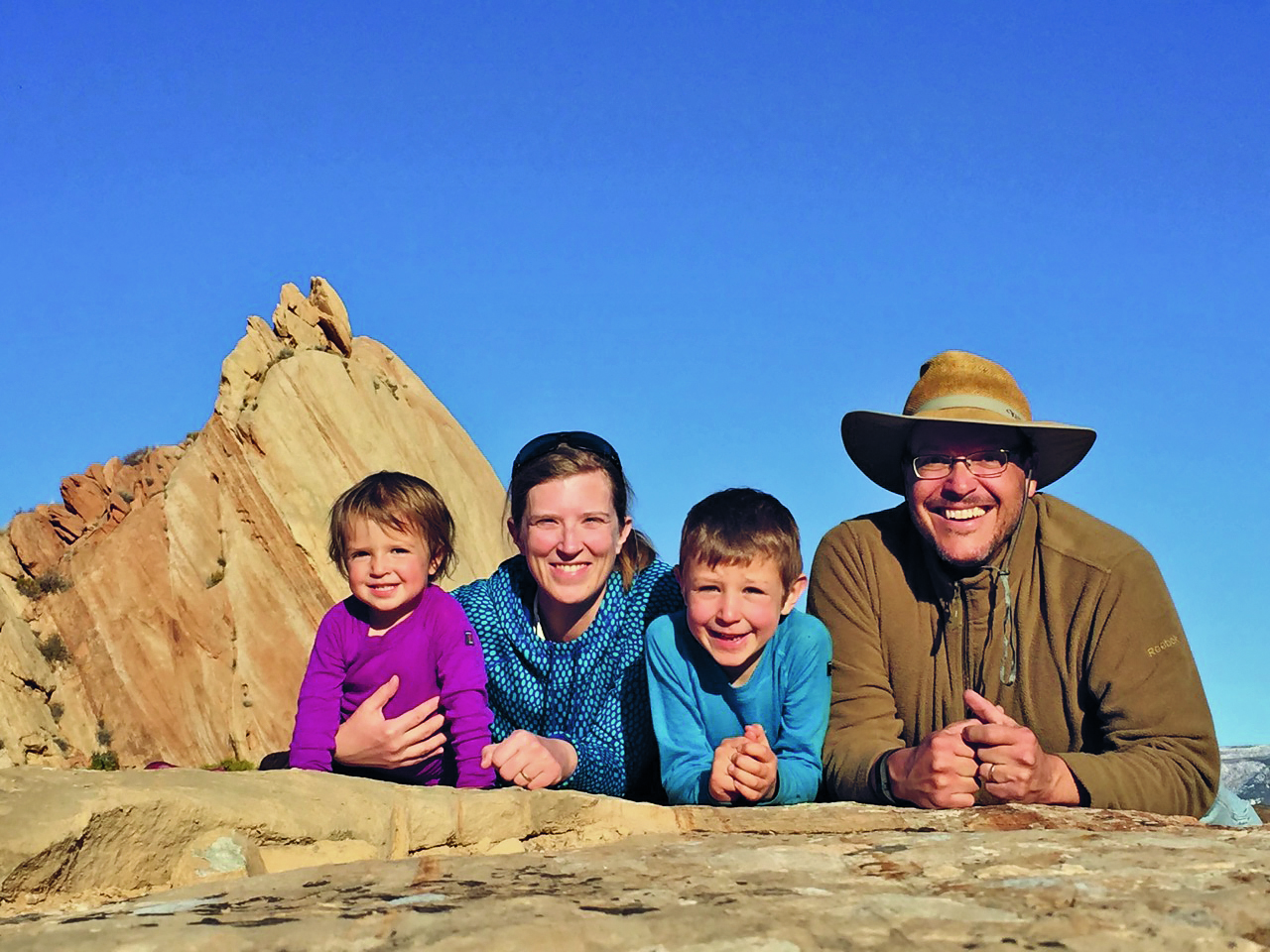 Marcio and his family smile with desert rocks in the background