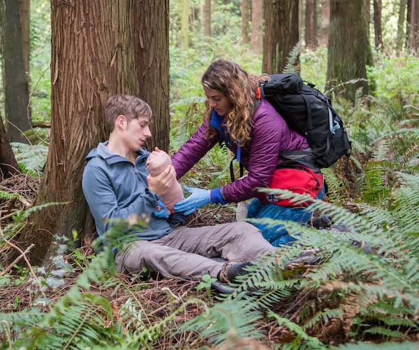two NOLS Wilderness Medicine students practice their skills outdoors in a scenario 