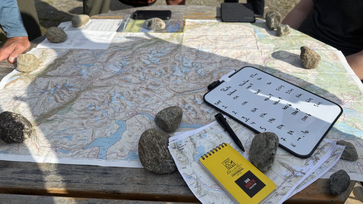 Maps of route and notes held down on table with rocks.
