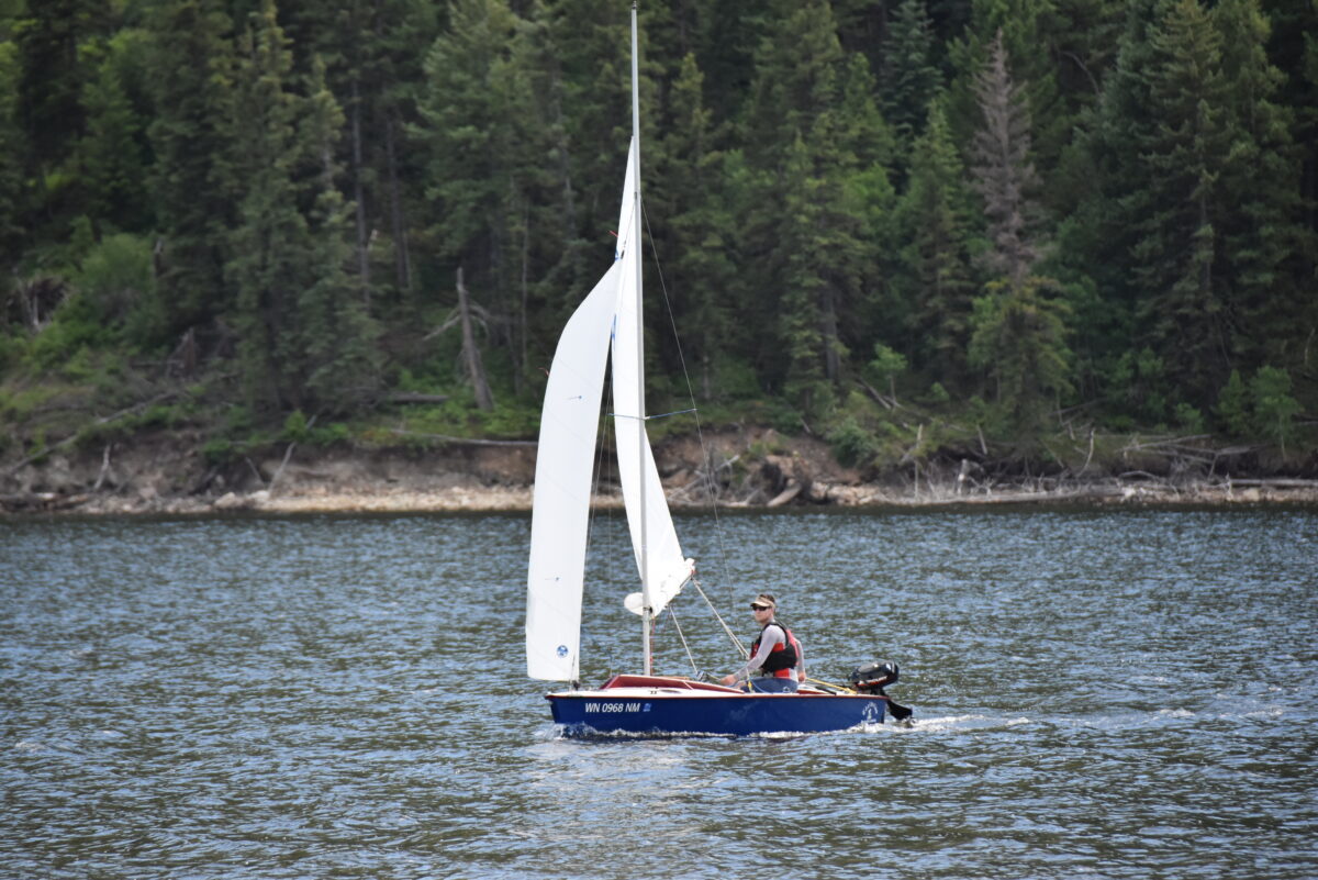 One crew member sails the dingy on slightly choppy water.