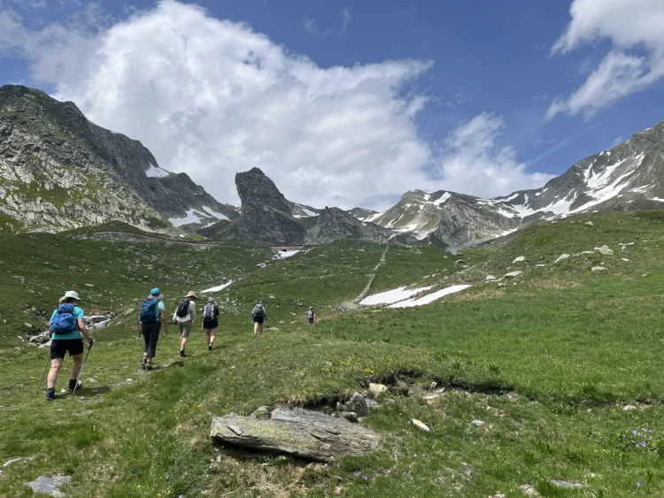 Hikers walk up the trail towards a mountain pass.