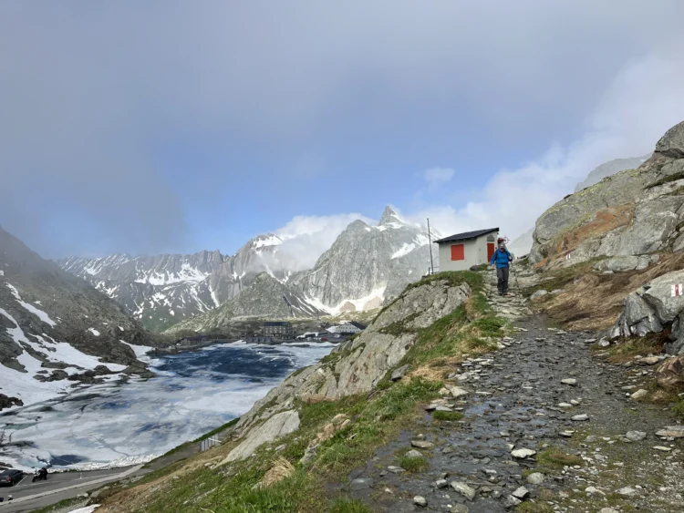 The trail leads towards a mountain hut and peaks.